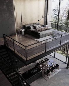 a bed sitting on top of a wooden floor next to a stair case in a living room