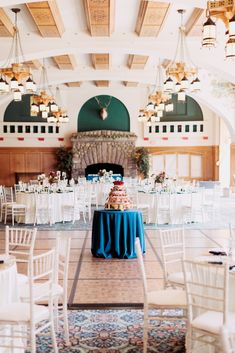 a room filled with white chairs and tables covered in blue cloths