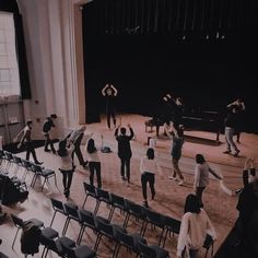 a group of people standing on top of a wooden floor in front of a stage