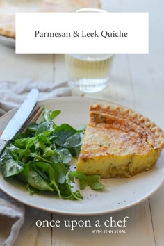 there is a piece of quiche on the plate next to a salad and fork