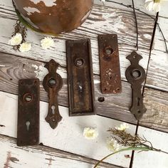 four old door handles on a white wooden surface with flowers in the vase behind them