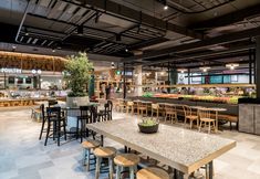 an empty restaurant with tables and chairs in the center, filled with food on display