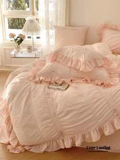 a bed with pink ruffled sheets and pillows