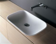 a white sink sitting on top of a wooden counter next to a faucet