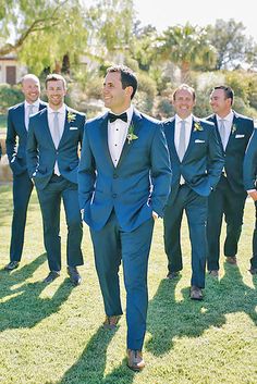 a group of men in suits walking across a field