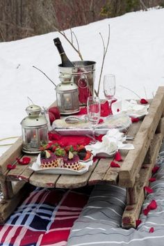 a picnic table set up in the snow with food and drinks on it, including strawberries