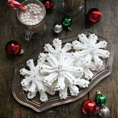 there is a tray with snowflakes on it next to two cups and candy canes