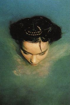 a woman is submerged in the water with her hair up