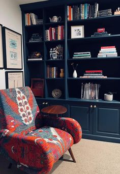 a chair and table in front of a bookcase with books on the shelves behind it