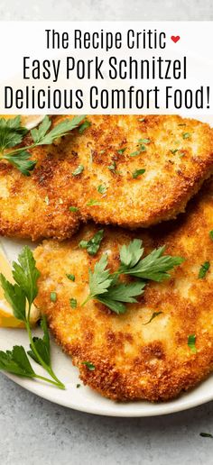 two crab cakes on a white plate with lemon wedges and parsley garnish