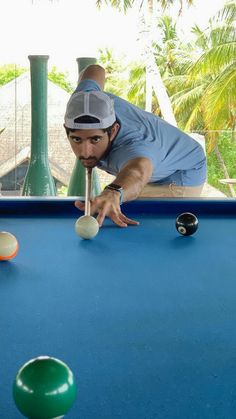 a man leaning over to hit a ball on a pool table with two balls in front of him