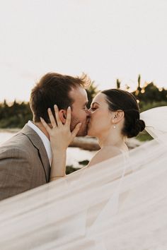 a bride and groom kissing under a veil