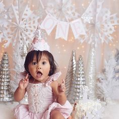 a baby girl in a pink dress with a tiara and snowflakes on it's head