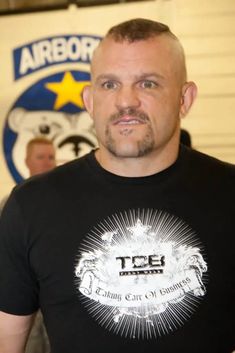 a bald man wearing a black tee shirt and standing in front of an air force emblem