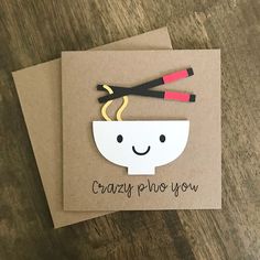 two greeting cards with chopsticks sticking out of them on top of a wooden table