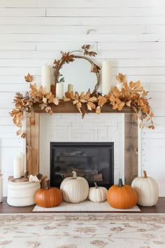 a mantel with pumpkins and candles on top of it in front of a mirror