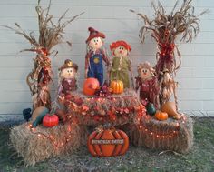 a display of scarecrows and pumpkins on hay bales