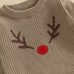 a sweater with a red rose on the front and two brown branches attached to it