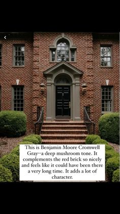 an old brick house with steps leading up to the front door and green bushes in front