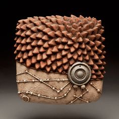 a ceramic sculpture of a hedgehog's head with spikes on it and wires running down the side