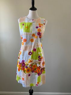 1960s-70s vibrant floral Longe Craft shift dress. The perfect dress for summer vacation! The cotton dress has pops of purple, hot pink, orange, olive green, and yellow flowers set against a beige, light blue, and lime green geometric background. Perfect for the beach, lounging around the house, or summer weekend fun. The dress zips up the back and has pockets. The cotton is sheer. Union made in the USA. Condition: Excellent vintage condition. Measurements: Size: small. Measurements taken when ga Mod Summer Beach Dresses, Summer Mod Beach Dresses, Lined Mod Summer Dresses, 1970s A-line Summer Dress, 1970s Style Cotton Summer Dress, Spring Floral Print Mod Dresses, Multicolor 1970s Spring Dresses, Mod Floral Print Spring Dress, 1970s Floral Beach Dresses