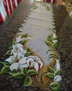 the table is decorated with white flowers and green leaves on it, along with red chairs