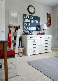 a bedroom with a white dresser, mirror and clock on the wall in front of it