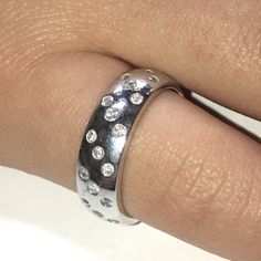 a woman's hand with a silver ring on top of her finger and diamonds in the middle