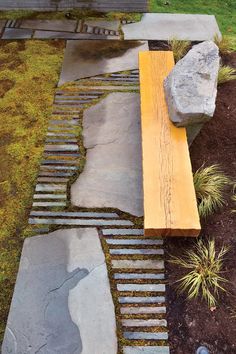 a wooden bench sitting on top of a grass covered field next to a stone walkway