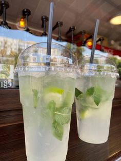 two glasses filled with ice and limeade sitting on a table