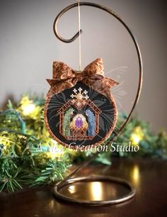 a cross stitch ornament hanging from a metal ring on top of a wooden table