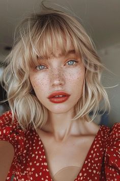 Blonde woman with bangs and freckles, wearing red dress with small print, looking at the camera. Ponytail And Bangs, Bangs Cut, Bangs Styles, Shaggy Bob Hairstyles, Hairstyles For Fine Hair, Trendy Bob Hairstyles, Wavy Bob Haircuts, Neutral Blonde