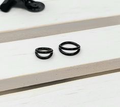 two black rings sitting on top of a white table next to a pair of shoes