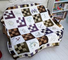 a couch covered in a patchwork quilt next to a book shelf