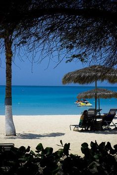 chairs and umbrellas on the beach with blue water