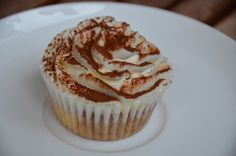 a cupcake with white frosting and brown sprinkles on it sitting on a plate