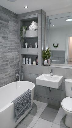 a white bath tub sitting next to a toilet under a bathroom mirror above a sink