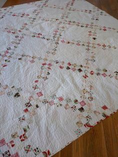 an old quilt is laying on the floor in front of a wooden floor with wood floors