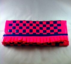 a pink and black checkered case sitting on top of a bed