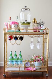 a gold bar cart with drinks and glasses on it's top shelf for sale