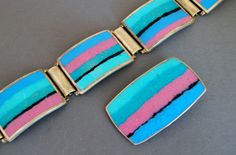 "This Perli German Mid Century modern matte enamel bracelet and matching pendant feature the colors of a southwestern sunrise - blue, pink, teal, and black. The bracelet is signed PERLI on the clasp; the matching pendant has no marks. Both pieces have black counter enamel backs and are silver metal over copper. The enamel is in excellent condition free of any problems. Era: 1950's - early 1960's Measures: Bracelet is 7 3/8\" long x 7/8\" wide. Pendant measures 1 5/8\" long x 1\" wide Excellent C Gold Fox, Bracelet Pendant, Jade Ring, Enamel Bracelet, Gold Brooches, Screw Back Earrings, Star Signs, Link Bracelets, Vintage Rings