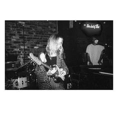 a woman playing a guitar while standing next to a man with a microphone in front of her