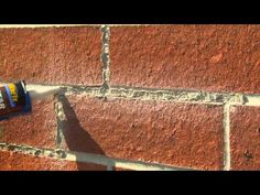 a spray can is being used to paint a brick wall with orange and white colors