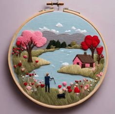 an embroidery project with a man and his dog on the grass near a lake, surrounded by flowers