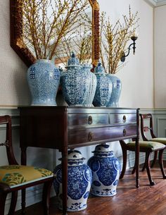 blue and white vases sit on top of a wooden table in front of a mirror