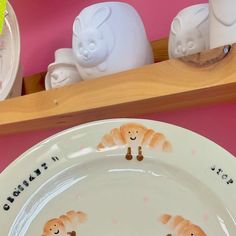 a white plate topped with orange cats on top of a pink tablecloth covered shelf