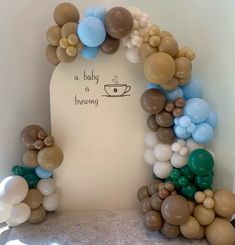 a baby is brewing sign surrounded by balloons in the shape of a cup and saucer