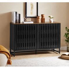 a black cabinet with wooden slats on top in a living room next to a white rug