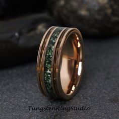 a gold ring with green moss inlays on the side and two bands around it