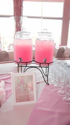 two pink candles sitting on top of a table next to wine glasses and a sign